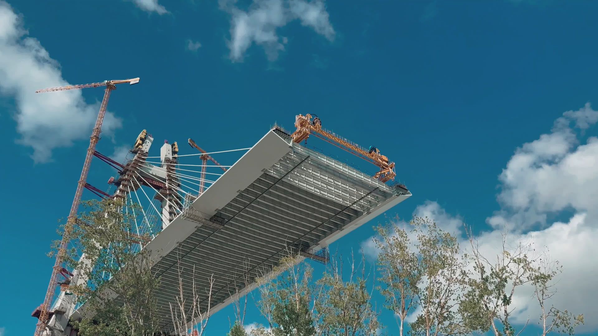Montaje con grúas de un tramo de puente atirantado contra el cielo
